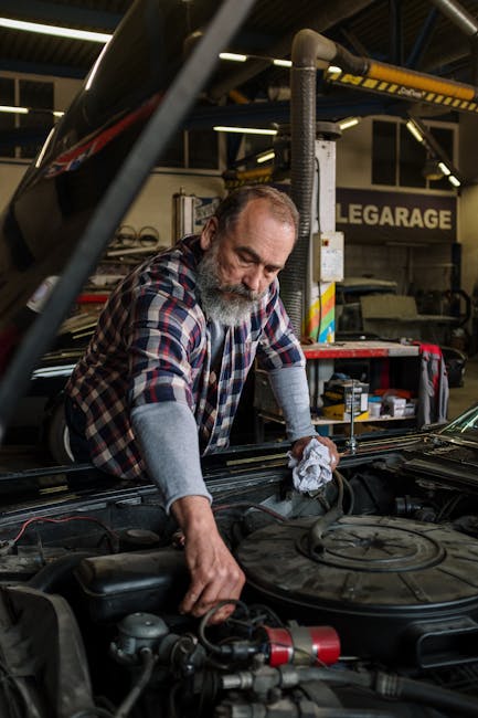 A bearded mechanic repairs a car engine inside a garage workshop, ensuring quality service.