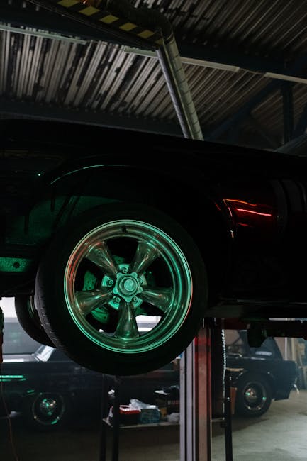Close-up of a car wheel illuminated by neon lights in a garage.