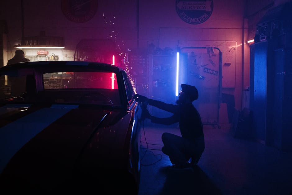 A mechanic works on a car in a neon-lit garage, creating a vibrant, moody atmosphere.