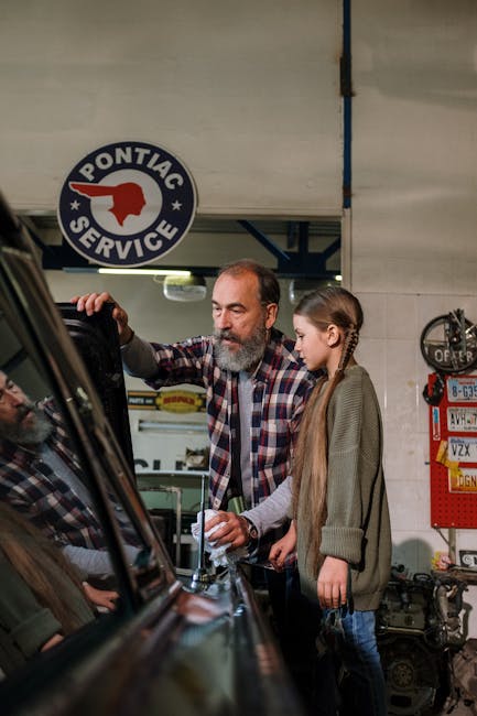 A father teaching his daughter about car repairs in a garage.